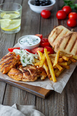 Greek dish gyros with chicken, french fries, tomatoes, onions and pita. Greek cuisine.
