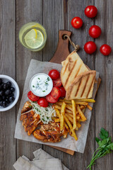 Greek dish gyros with chicken, french fries, tomatoes, onions and pita. Greek cuisine.