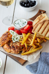 Greek dish gyros with chicken, french fries, tomatoes, onions and pita. Greek cuisine.