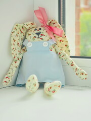 Handmade Easter soft toy. DIY Easter Bunny sitting upon window. Sewn rabbit. Selective focus on the face.