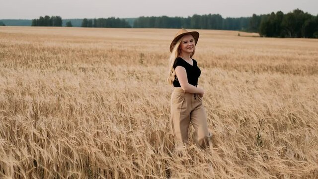 Beautiful girl walking in wheat field in summer. Attractive young woman touching grain and turning to warm sunlight in nature. Natural healthy summertime lifestyle. freedom concept.