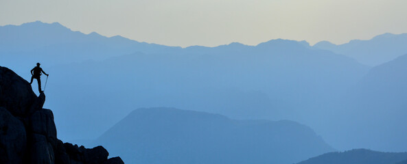 mountaineer watching the mountains at the top of the high rock