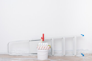 white paint buckets and a ladder stand against a white wall, on top there is a place for an inscription © kurgu128