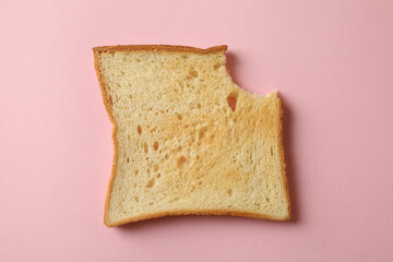 Bitten toast bread on pink background, close up
