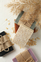 Reed branches and natural soap on white table