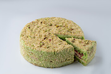 Pistachio torte with nuts crumbs, one slice separated, isolated on white background