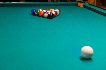 Sports game of billiards on a green cloth. Multi-colored billiard balls with numbers on a pool table