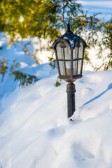 Black street lamp covered with snow