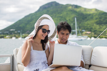 Young couple having fun on the boat with a laptop