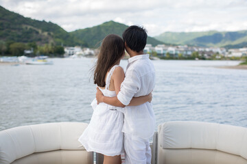 Fototapeta premium Young couple is traveling on a yacht in the Indian ocean. On the bow of the boat, a loving family embraces