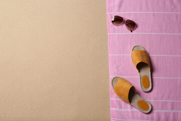 Sunglasses, shoes, blanket and space for text on beach sand, top view. Summer vacation