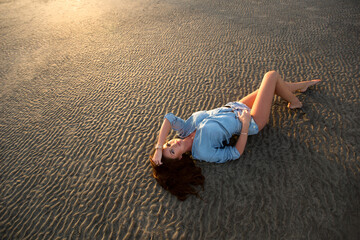 Young girl lying on the sand at sunset