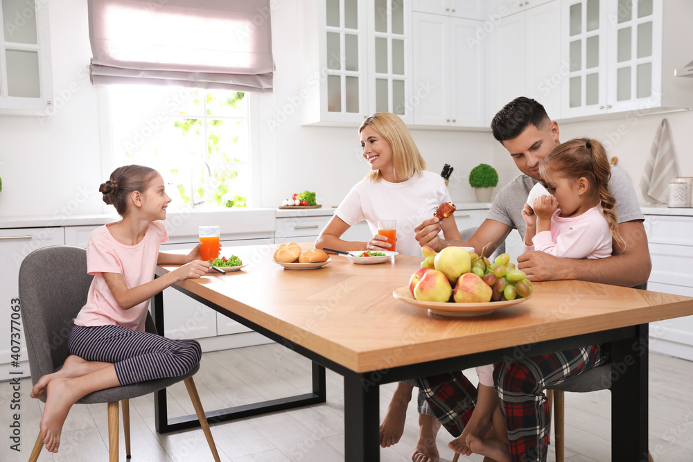 Wall mural Happy family having breakfast together at table in modern kitchen