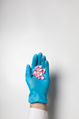 A hand in a glove holds a handful of pills