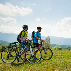 Obraz premium ACTIVE Young couple biking on a forest road in mountain on a spring day