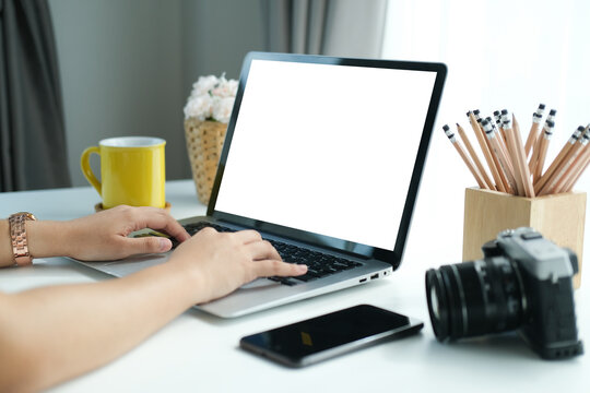Close up view of photographer hands typing on laptop computer at comfortable workspace.