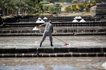 People collect the salt on a Sunny day on the shores of the Indian ocean in Mauritius.