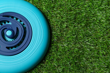 Light blue plastic frisbee disk on green grass, top view. Space for text