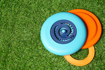 Plastic frisbee disks and ring on green grass, flat lay. Space for text