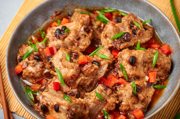 Dim Sum Pork Spare Ribs or Pai Guat in gray bowl on dark concrete table top. Chinese cantonese cuisine steamed spareribs dish with black soybeans. Asian food. Close up