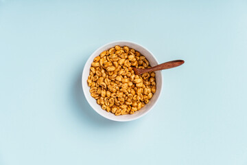 Dry breakfast air caramel wheat in a deep bowl on a blue background, top view