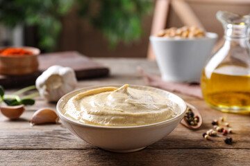 Delicious creamy hummus in dish on wooden table
