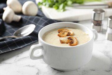 Delicious cream soup with mushrooms on white marble table