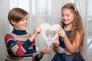 Two happy kids, girl and boy with valentines heart candle