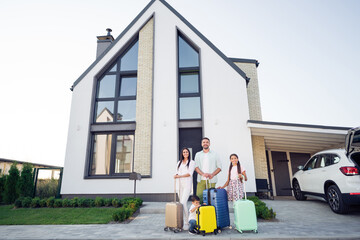 Photo portrait of smiling big full family with small kids keeping baggage near car relocating ready to enter home apartment