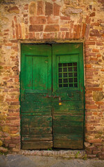 An old wooden door in a disused residential building in the historic centre of the medieval town of Monticiano in Siena Province, Tuscany, Italy
