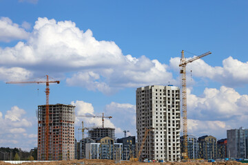 Fototapeta na wymiar View of tall cranes and houses under construction.