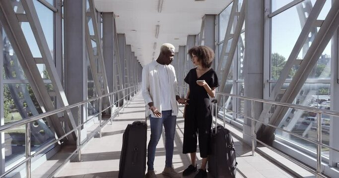 Afro american couple young family on their honeymoon two friends man and woman stand in airport terminal looking for right way point hotel looks at map and into mobile phone quarreling angry arguing
