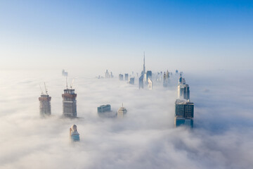 Aerial view of Dubai futuristic urban city skyline covered in dense fog during winter season