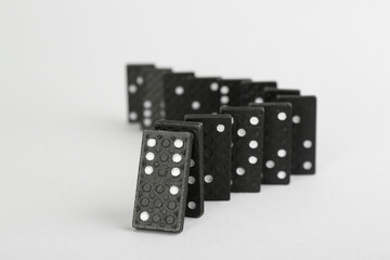 Black domino tiles falling on white background