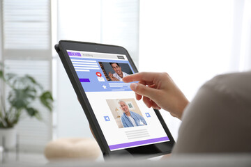 Fototapeta na wymiar Young woman visiting online dating site via tablet indoors, closeup