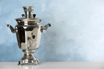 Metal samovar on grey table against light blue background, space for text. Russian tea culture