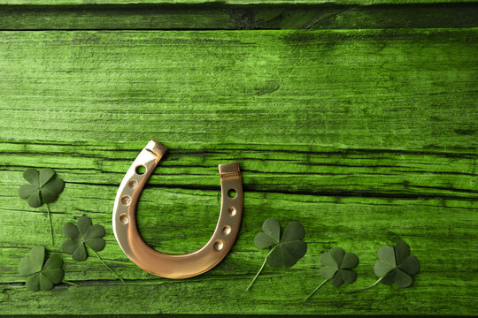 Clover leaves and horseshoe on green wooden table, flat lay with space for text. St. Patrick's Day celebration - Powered by Adobe