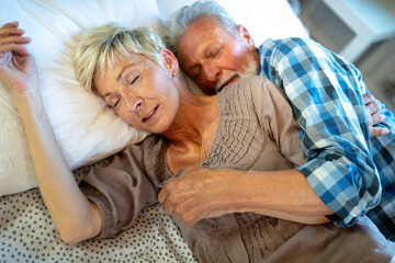 Happy senior couple embracing, sleeping together in bedroom