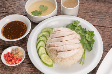 Hainanese chicken rice on a white table background, Steamed chicken rice with spicy sauces and chicken soup,