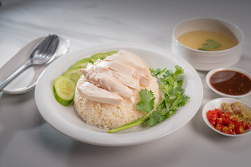Hainanese chicken rice on a white table background, Steamed chicken rice with spicy sauces and chicken soup,
