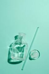 Top view of glass and little cosmetics liquid in it, lab dropper on the blue background