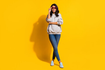 Fototapeta na wymiar Full body photo of young dark skin woman hold wear sunglass jeans hoodie isolated on yellow color background