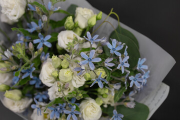 A bouquet of flowers on a dark background. Spiral assembly technique in a white decorative package.