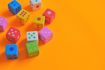 Board games concept. games of chance.  Multicolored cubes set on a bright orange background.Figures and numbers concept. copy space.