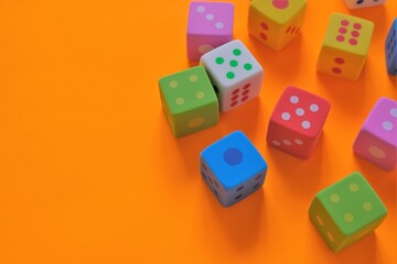 Board games concept. games of chance.  Multicolored cubes set close-up on a  orange background.Figures and numbers concept. copy space.