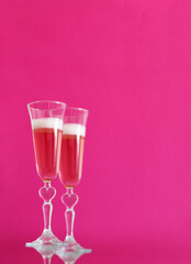 two glasses of champagne on  pink background