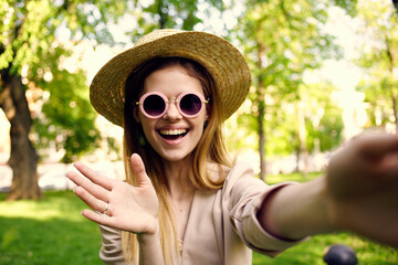 Cheerful woman in sunglasses outdoors in the park in summer walk