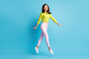 Fototapeta na wymiar Full length photo portrait of excited girl walking jumping up isolated on pastel blue colored background