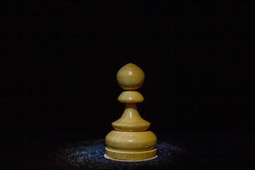 wooden chess pawn on a black background