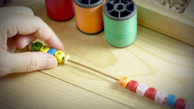 String a bracelet Wooden letter beads of keep fighting word, Close up woman hand string with a colourful Wooden letter beads, mood and tone concept.